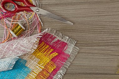 masaüzerinde çok renkli, pürüzlü pamuklu kumaş, iğne işi için alet ve iplikler