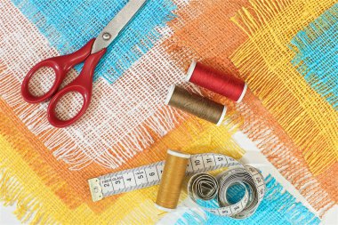 masaüzerinde çok renkli, pürüzlü pamuklu kumaş, iğne işi için alet ve iplikler