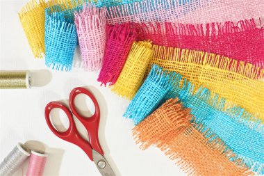 masaüzerinde çok renkli, pürüzlü pamuklu kumaş, iğne işi için alet ve iplikler