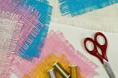 masaüzerinde çok renkli, pürüzlü pamuklu kumaş, iğne işi için alet ve iplikler