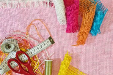 masaüzerinde çok renkli, pürüzlü pamuklu kumaş, iğne işi için alet ve iplikler