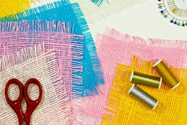 masaüzerinde çok renkli, pürüzlü pamuklu kumaş, iğne işi için alet ve iplikler