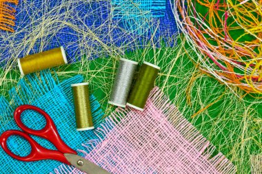 masaüzerinde çok renkli, pürüzlü pamuklu kumaş, iğne işi için alet ve iplikler