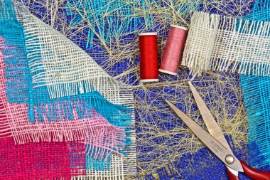 masaüzerinde çok renkli, pürüzlü pamuklu kumaş, iğne işi için alet ve iplikler