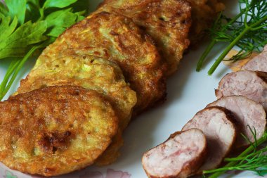 bir renk çanak üzerinde dilimlenmiş sosis ve otlar ile sıcak kabak börek.