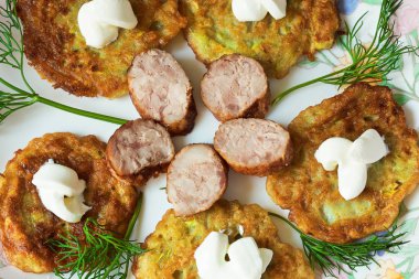 bir renk çanak üzerinde dilimlenmiş sosis ve otlar ile sıcak kabak börek.