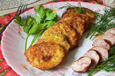 bir renk çanak üzerinde dilimlenmiş sosis ve otlar ile sıcak kabak börek.