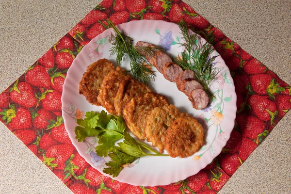 bir renk çanak üzerinde dilimlenmiş sosis ve otlar ile sıcak kabak börek.