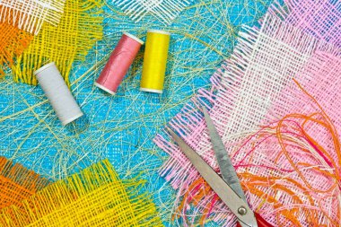 masaüzerinde çok renkli, pürüzlü pamuklu kumaş, iğne işi için alet ve iplikler