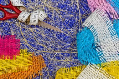 masaüzerinde çok renkli, pürüzlü pamuklu kumaş, iğne işi için alet ve iplikler