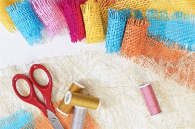masaüzerinde çok renkli, pürüzlü pamuklu kumaş, iğne işi için alet ve iplikler