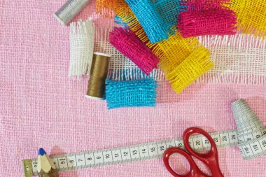 masaüzerinde çok renkli, pürüzlü pamuklu kumaş, iğne işi için alet ve iplikler