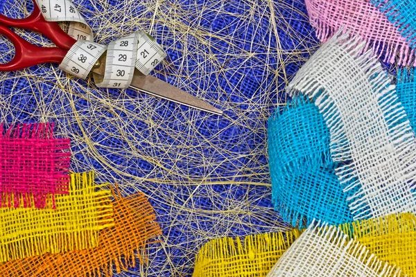 masaüzerinde çok renkli, pürüzlü pamuklu kumaş, iğne işi için alet ve iplikler