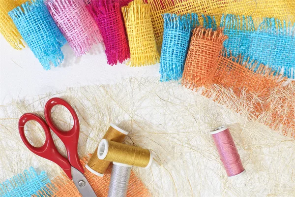 masaüzerinde çok renkli, pürüzlü pamuklu kumaş, iğne işi için alet ve iplikler