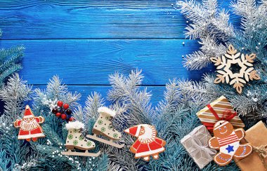 Süslemeleri ve ladin dalları ile mavi ahşap arka plan üzerinde Noel zencefilli kurabiye ve hediyeler.