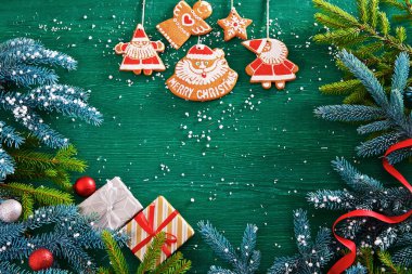 köknar dalları, Noel zencefilli kurabiye, hediyeler ve yeşil ahşap arka plan üzerinde süslemeleri. kartpostallar için