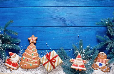 Süslemeleri ve ladin dalları ile mavi ahşap arka plan üzerinde Noel zencefilli kurabiye ve hediyeler.