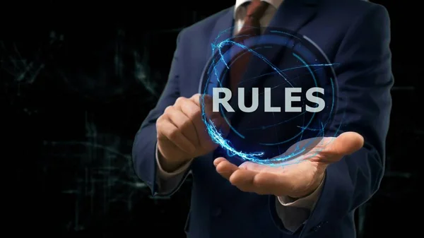 Businessman shows concept hologram Rules on his hand — Stock Photo, Image