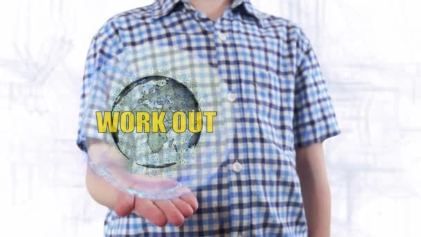 Young man shows a hologram of the planet Earth and text Work out — Stock Video