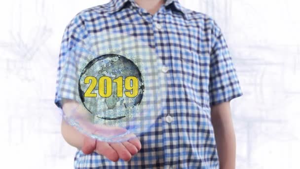 Jeune homme montre un hologramme de la planète Terre et le texte 2019 — Video