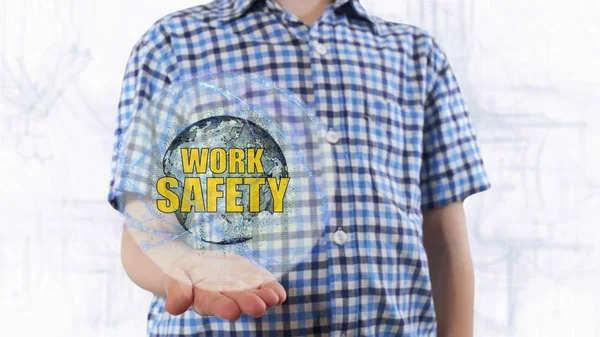 Young man shows a hologram of the planet Earth and text Work safety — Stock Photo, Image