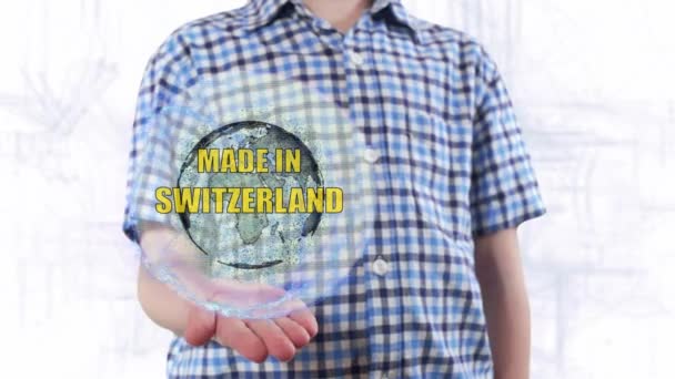 Young man shows a hologram of the planet Earth and text Made in Switzerland — Stock Video