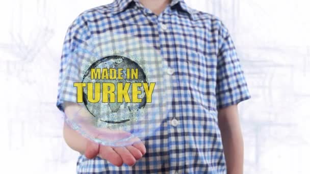 Young man shows a hologram of the planet Earth and text Made in Turkey — Stock Video