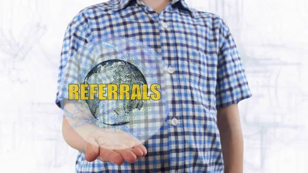 Young man shows a hologram of the planet Earth and text Referrals — Stock Photo, Image