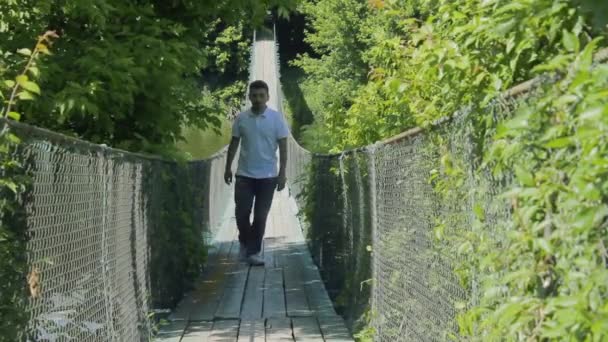 Человек идет по канатному мосту — стоковое видео