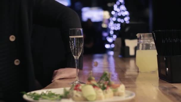 La mano de los camareros pasa una copa de champán a un hombre sobre el fondo borroso de un mostrador de bar — Vídeo de stock