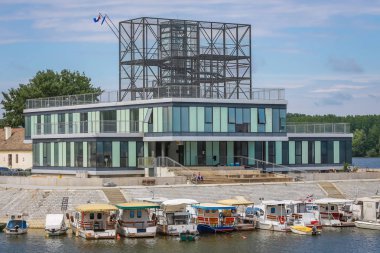 Vukovar, Hırvatistan - 14 Mayıs 2018: Deniz kenarı Dunav Nehri'nin Vukovar, Hırvatistan'da çağdaş bir bina önünde demirleyen teknelerin bir görünüm.