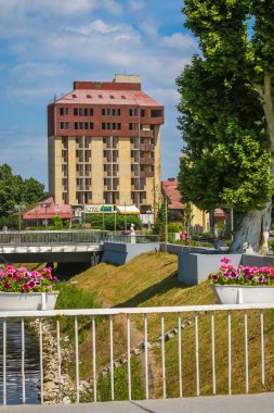 Vukovar, Hırvatistan - 14 Mayıs 2018: Görünüm çiçek ve yaya köprüsü Nicolier Jean Michel nehir içinde belgili tanımlık geçmiş Vukovar, Hırvatistan için terk edilmiş otel Dunav ile Vuka arasında.