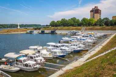 Vukovar, Hırvatistan - 14 Mayıs 2018: Dunav Hotel Dunav ve çapraz Hırvat Savaşı savunucuları Vukovar, Hırvatistan için arka planda anısına Nehri'nin kıyısında demirleyen teknelerin bir görünüm.
