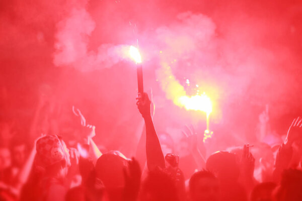 Football fans celebrating victory by burning torches.