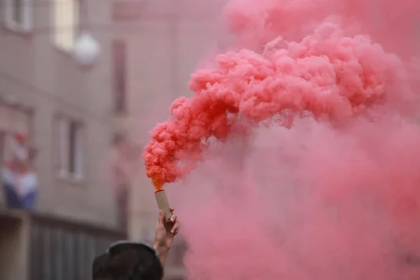 A man holding a hand flare with red smoke.