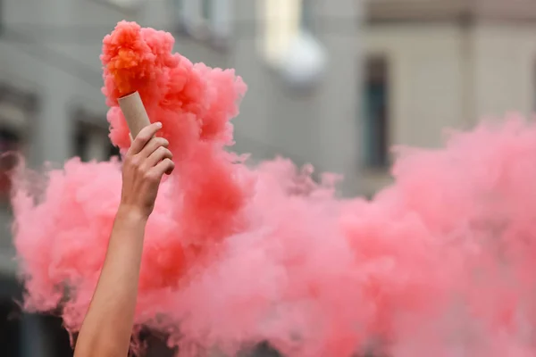 A man holding a hand flare with red smoke.