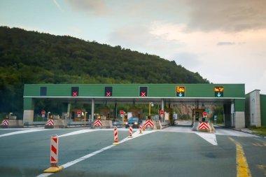 Ostrovica, Croatia - August 1th, 2018 : Cars driving on the highway tollbooth Ostrovica at sunset in Ostrovica, Croatia. clipart