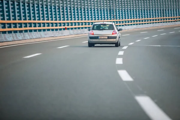 Rear view of car driving on the highway with noise barrier.