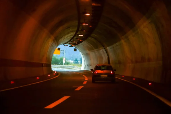 左两线弯曲公路隧道与一辆汽车驾驶在正确的路线到出口在末端 — 图库照片