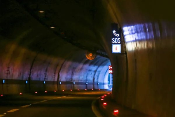 Sos sign in the tunnel on highway with exit of the tunnel in the background.