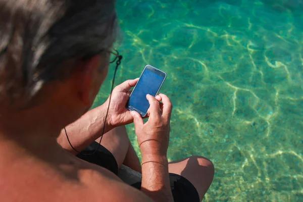 Muž Brýlemi Držení Smartphone Při Posezení Molu Moře — Stock fotografie