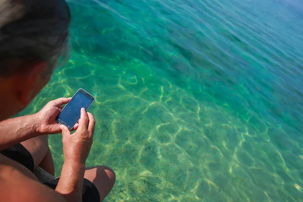 Muž Který Držel Smartphone Při Posezení Molu Moře — Stock fotografie