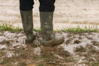 A person in rubber boots standing in the mud. clipart