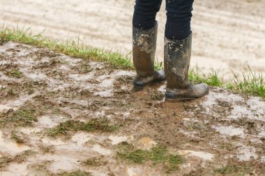 A person in rubber boots standing in the mud. clipart