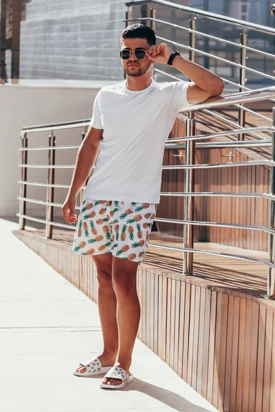 Portrait of young stylish man near the pool deck on sunny summer day. Lifestyle.