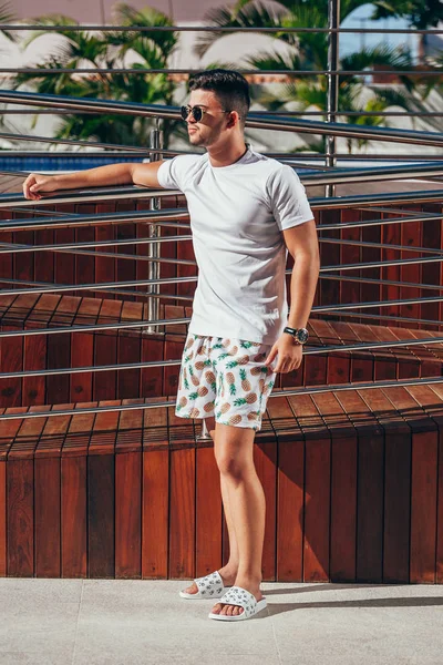 Portrait of young stylish man near the pool deck on sunny summer day. Lifestyle.