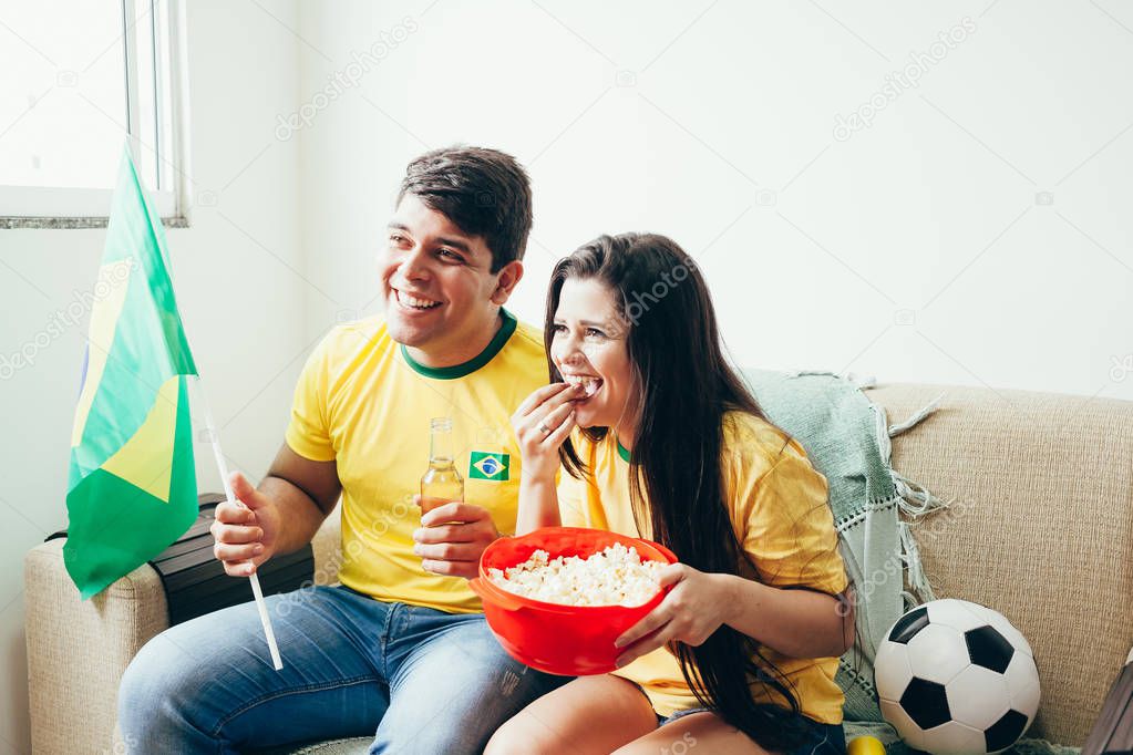 Couple watching soccer game on television, celebrating goal and screaming