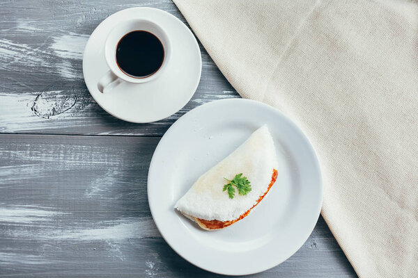 Brazilian Tapioca with cheese (coalho) and coffee over a wooden table