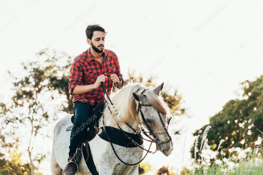 Young man riding white horse on the countryside