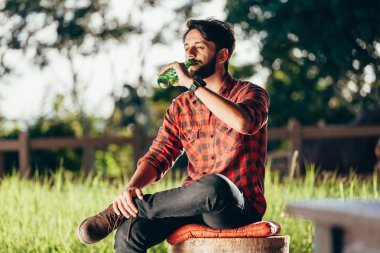 Bankta oturan ve mera ve arka planda corral bira içme Genç çiftçi